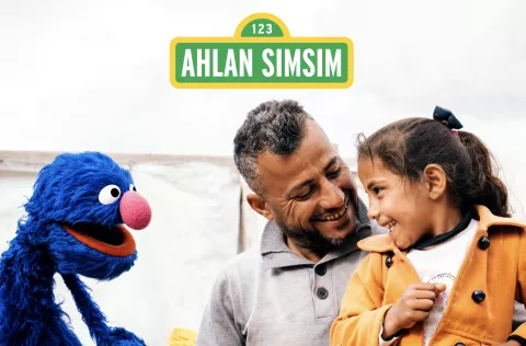 Girl Smiling while looking at a puppet from Ahlan Simsim 